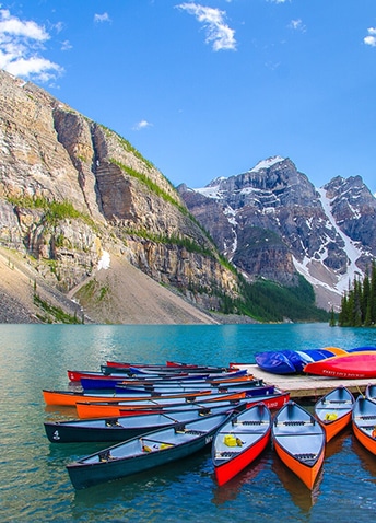 Several colorful canoes docked at a mountainside pier