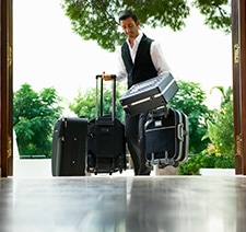 A man walking into a hotel with a number of suitcases.